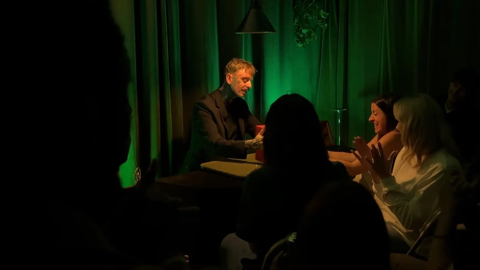 Simon working the table with the audience under green light